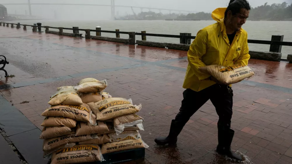 A worker moves sandbags in the rain at River Street as Tropical Storm Debby moves towards Georgia, in Savannah, Georgia, U.S., August 5, 2024. REUTERS/Marco Bello