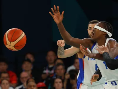 Paris 2024 Olympics - Basketball - Men's Quarterfinal - France vs Canada - Bercy Arena, Paris, France - August 06, 2024. Frank Ntilikina of France is seen with his headband over his eyes while players interact during the match. REUTERS/Brian Snyder