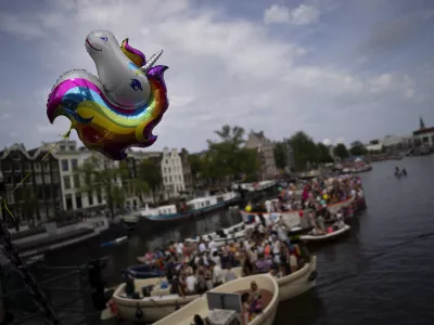 A rainbow unicorn balloon flies from a bridge as boats line the Dutch capital's historic canals Saturday, Aug. 3, 2024, for the Canal Parade, the most popular event of a nine-day Pride Amsterdam festival that attracts tens of thousands of visitors to the city. The Canal Parade event drew 80 boats from organizations ranging from LGBTQ+ groups to the Dutch government, police, military and Olympic committee. Pride Amsterdam, which started in 1996, is one of the world's largest pride festivals. (AP Photo/Peter Dejong)