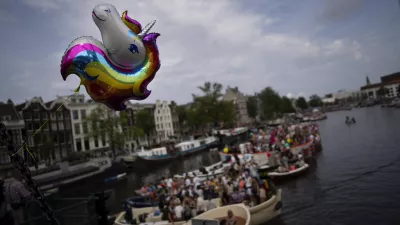 A rainbow unicorn balloon flies from a bridge as boats line the Dutch capital's historic canals Saturday, Aug. 3, 2024, for the Canal Parade, the most popular event of a nine-day Pride Amsterdam festival that attracts tens of thousands of visitors to the city. The Canal Parade event drew 80 boats from organizations ranging from LGBTQ+ groups to the Dutch government, police, military and Olympic committee. Pride Amsterdam, which started in 1996, is one of the world's largest pride festivals. (AP Photo/Peter Dejong)