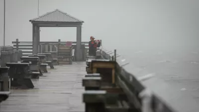 A woman uses her phone to capture images from the pier as Tropical Storm Debby drifts in the East Coast, in Myrtle Beach, South Carolina, U.S., August 7, 2024. REUTERS/Marco Bello