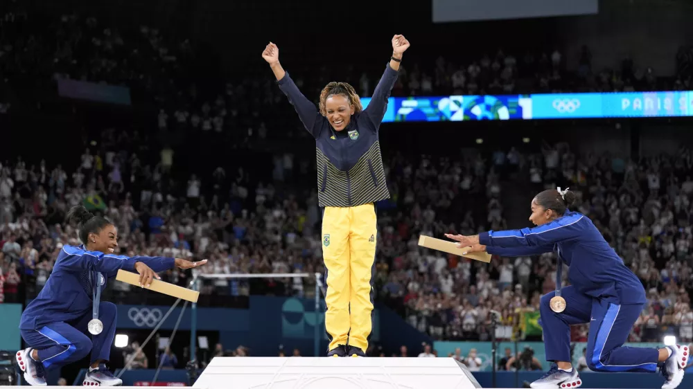 Silver medalist Simone Biles, of the United States, left, and bronze medalist Jordan Chiles, of the United States, right, bow to gold medalist Rebeca Andrade, of Brazil, during the medal ceremony for the women's artistic gymnastics individual floor finals at Bercy Arena at the 2024 Summer Olympics, Monday, Aug. 5, 2024, in Paris, France. (AP Photo/Abbie Parr)