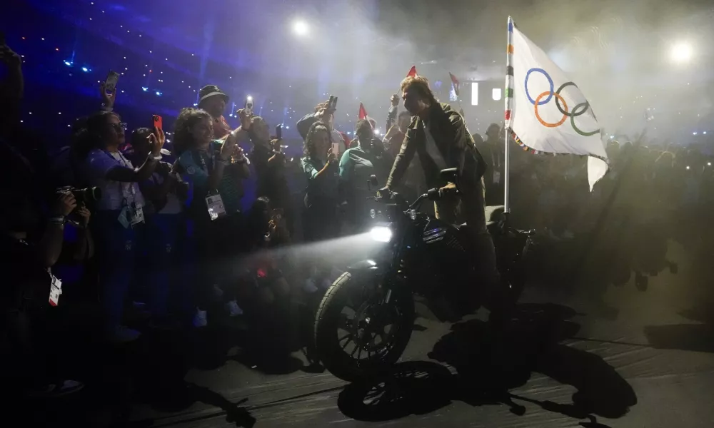 Tom Cruise rides a motorbike with the Olympic flag attached during the 2024 Summer Olympics closing ceremony at the Stade de France, Sunday, Aug. 11, 2024, in Saint-Denis, France. (AP Photo/Ashley Landis)