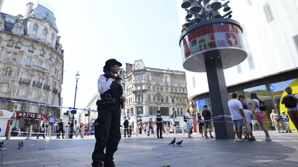 A Police officer stands at the scene in Leicester Square, as a man was arrested with the accusation of stabbing an 11-year-old girl and 34-year-old woman, in London, Monday Aug. 12, 2024. (James Manning/PA via AP)