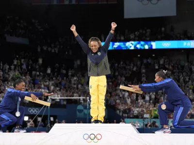 Silver medalist Simone Biles, of the United States, left, and bronze medalist Jordan Chiles, of the United States, right, bow to gold medalist Rebeca Andrade, of Brazil, during the medal ceremony for the women's artistic gymnastics individual floor finals at Bercy Arena at the 2024 Summer Olympics, Monday, Aug. 5, 2024, in Paris, France. (AP Photo/Abbie Parr)