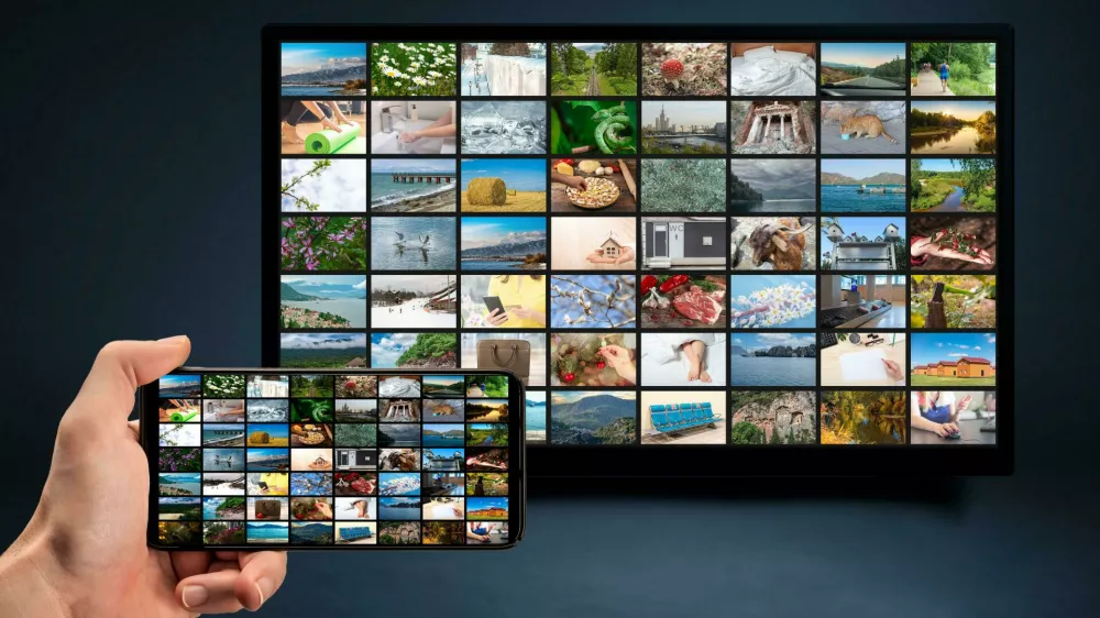 2E9EAW6 man holding mobile phone with many icons of video service on demand on background Oline TV VOD provider. Interface of video distribution service. Subs