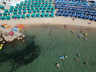 A drone view shows people swimming in the sea and umbrellas on a beach in Santa Marinella, north of Rome, Italy, August 13, 2024 REUTERS/Guglielmo Mangiapane