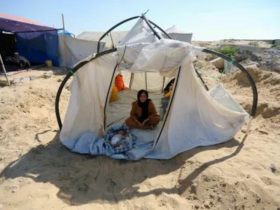 A displaced Palestinian woman and a child shelter in a cemetery, as Gaza health ministry announced that death toll has surpassed 40,000, amid the Israel-Hamas conflict, in Khan Younis, in the southern Gaza Strip, August 15, 2024. REUTERS/Hatem Khaled   TPX IMAGES OF THE DAY