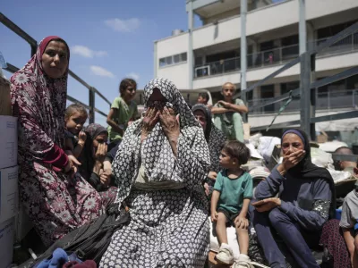 Palestinian women weep on a truck as she evacuates a school that had been her shelter, in eastern Deir al-Balah, Gaza Strip, Friday, Aug. 16, 2024, after the Israeli military dropped leaflets asking civilians to evacuate from the area, saying forces plan to respond to rocket fire that targeted Israel. (AP Photo/Abdel Kareem Hana)