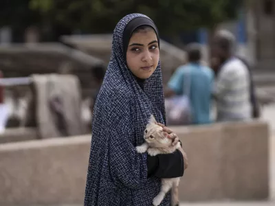 A Palestinian girl carries her cat as she evacuates a school that had been her shelter, in eastern Deir al-Balah, Gaza Strip, Friday, Aug. 16, 2024, after the Israeli military dropped leaflets asking civilians to evacuate from the area, saying forces plan to respond to rocket fire that targeted Israel. (AP Photo/Abdel Kareem Hana)