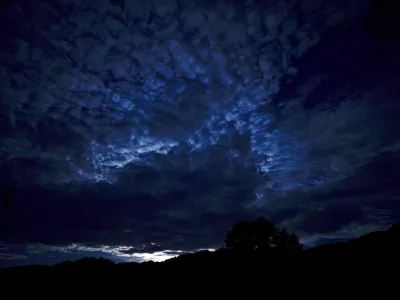 Clouds are lit by moon light as it rises behinds the Carnic Alps in the town of Obertilliach, in the Austrian region of east Tyrol, Sunday, Aug. 18, 2024. (AP Photo/Andrew Medichini)