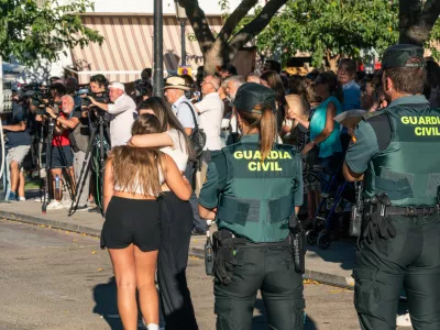 18 August 2024, Spain, Mocejon: Two Guardia Civil officers watch two girls embrace during the minute of silence for the murder of a minor at the door of the Mocejon Town Hall. The Mocejon City Council has ordered three days of national mourning for the murder of an 11-year-old minor who was playing soccer this morning with other children on the municipal soccer pitch "Angel Tardio" when he was attacked with a sharp object. Photo: Juan Moreno/EUROPA PRESS/dpa