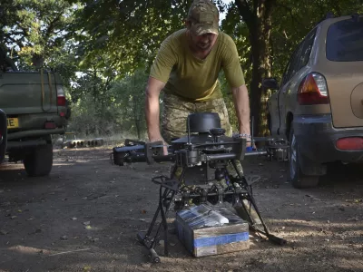 A soldier of Ukraine's 141st separate infantry brigade loads a drone with a parcel for soldiers on a mission at the frontline in Zaporizhzhia region, Ukraine, Monday, Aug. 19, 2024. (AP Photo/Andriy Andriyenko)