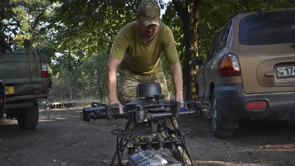 A soldier of Ukraine's 141st separate infantry brigade loads a drone with a parcel for soldiers on a mission at the frontline in Zaporizhzhia region, Ukraine, Monday, Aug. 19, 2024. (AP Photo/Andriy Andriyenko)