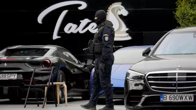 A masked gendarme patrols the courtyard of the residence of social media personality Andrew Tate during an early morning police search raid, on the outskirts of Bucharest, Romania, Wednesday, Aug. 21 2024. (AP Photo/ Vadim Ghirda)