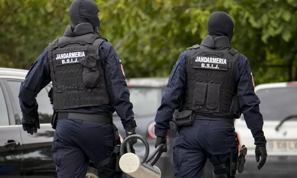 Gendarmes wearing balaclavas hold a battering ram used to break down a door outside the residence of internet influencer Andrew Tate during an early morning police search raid, on the outskirts of Bucharest, Romania, Wednesday, Aug. 21, 2024. (AP Photo/ Vadim Ghirda)