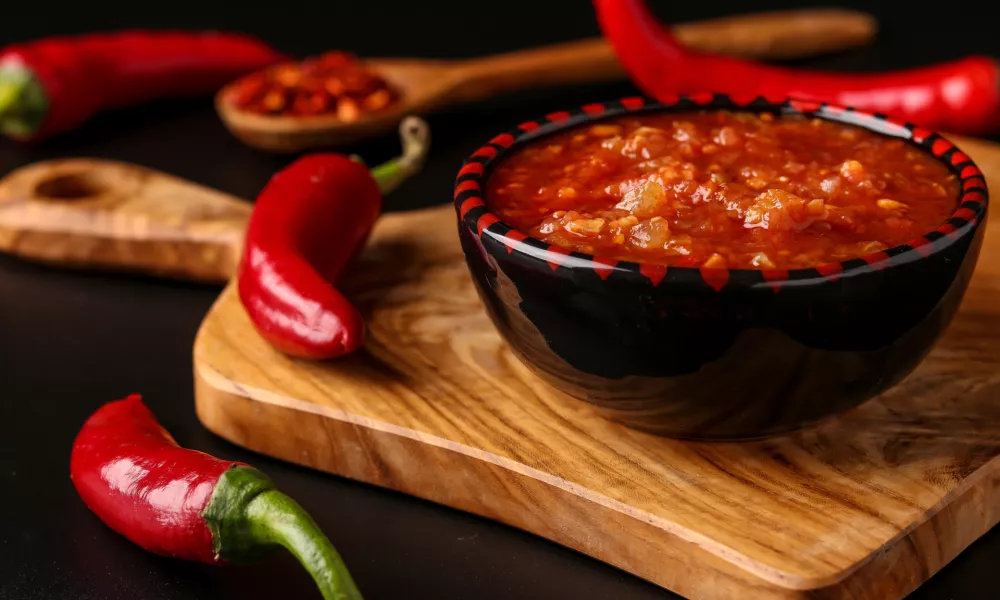 Traditional Maghrebi hot chili pepper sauce paste harissa on dark background, Tunisia and Arabic cuisine, horizontal orientation, closeup / Foto: Angelika Mostova