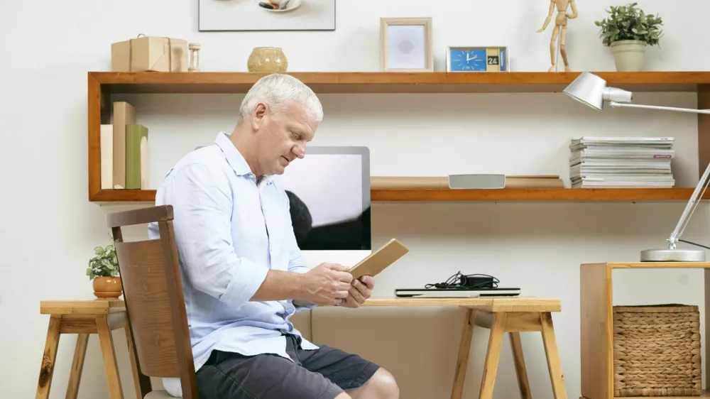 Mature programmer sitting at his working table at home and reading requirement specification on tablet computer / Foto: Istockphoto