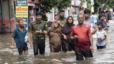 People carry their belongings and wade through flooded water to reach a temporary shelter in Feni, a coastal district in southeast Bangladesh, Friday, Aug. 23, 2024. (AP Photo/Fatima Tuj Johora)