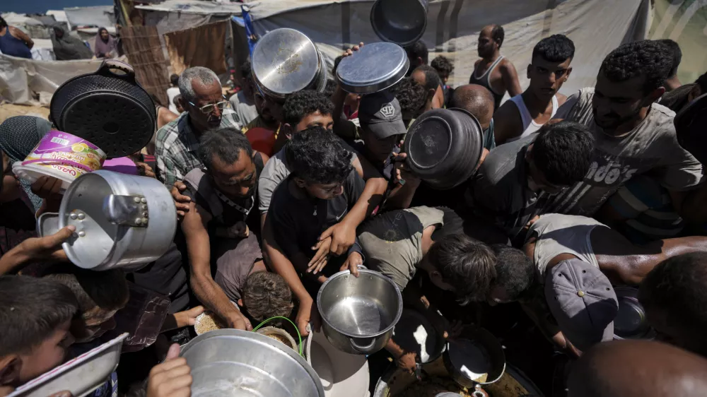 Displaced Palestinians at a food distribution center in Deir al Balah, central Gaza Strip, Friday, Aug. 23, 2024. (AP Photo/Abdel Kareem Hana)