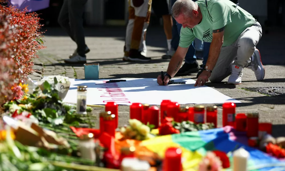 A man writes a message on a placard following an incident in which several individuals were killed after a man randomly stabbed passers-by with a knife at a city festival, in Solingen, Germany, August 24, 2024. REUTERS/Thilo Schmuelgen