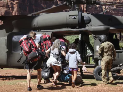 U.S. Army soldiers of the Arizona National Guard guide tourists trapped by flash flooding into a UH-60 Blackhawk, Saturday, Aug. 24, 2024, on the Havasupai Reservation in Supai, Ariz. (Maj. Erin Hannigan/U.S. Army via AP)