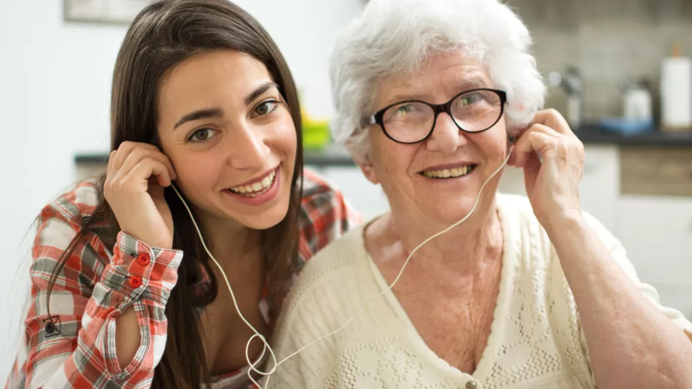 Granddaughter listening music with her grandmother at home. / Foto: Bojan89