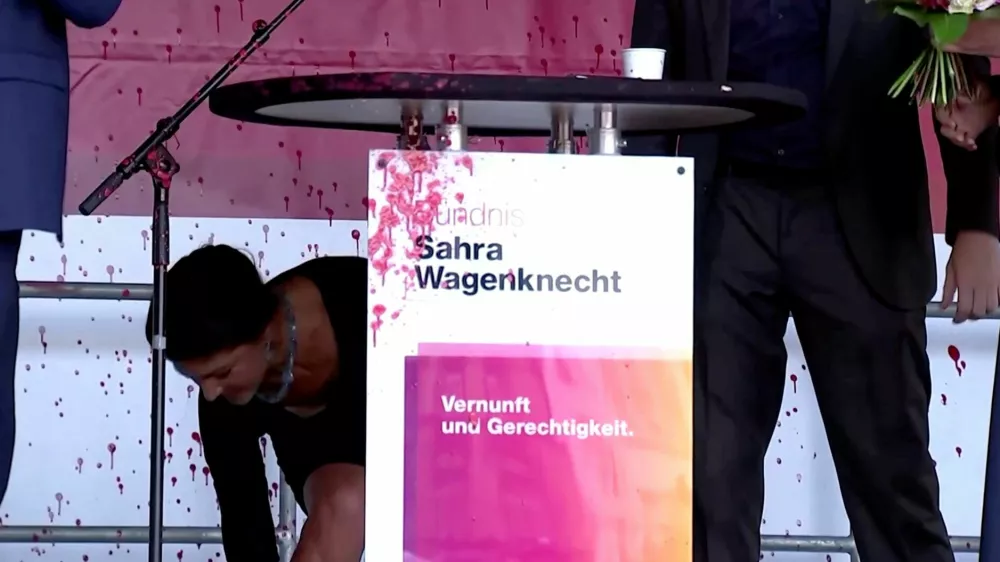 Sahra Wagenknecht, top candidate of Germany's Sahra Wagenknecht Alliance (BSW) party in the Thuringia state elections, takes cover after paint was thrown at the podium where she spoke during an election campaign rally in Erfurt, Germany, August 29, 2024, in this still image obtained from a video. Reuters TV via REUTERS