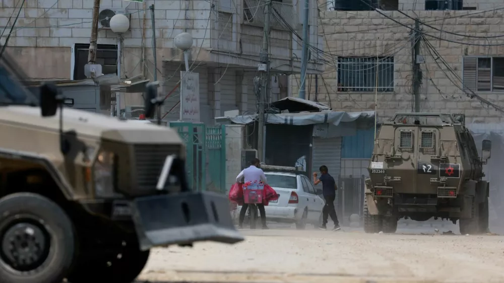 A Palestinian walks next to armoured vehicles during an Israeli raid in Jenin, in the Israeli-occupied West Bank, August 31, 2024. REUTERS/Ammar Awad