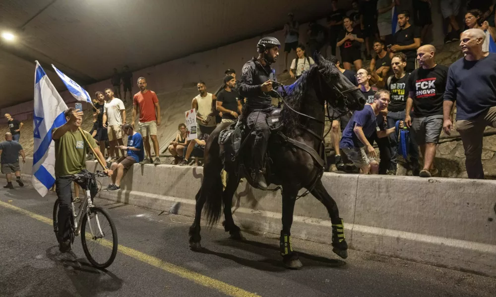 A police officer on a horse moves past people protesting for a deal for the immediate release of hostages held in the Gaza Strip by Hamas, in Tel Aviv, Israel, Sunday, Sept. 1, 2024. (AP Photo/Ohad Zwigenberg)