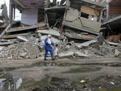 A displaced Palestinian mother, Wafaa Abdelhadi, walks past the rubble of a house destroyed in an Israeli strike as she returns to her shelter with her daughters Lynn and Roueida, after they got vaccinated against polio, in Deir Al-Balah, in the central Gaza Strip September 1, 2024. REUTERS/Ramadan Abed