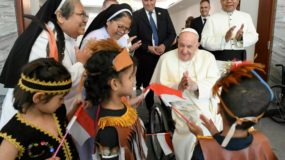 Pope Francis interacts with children as he meets with migrants, during his apostolic visit to Asia, in Jakarta, Indonesia September 3, 2024. Vatican Media/­Handout via REUTERS  ATTENTION EDITORS - THIS IMAGE WAS PROVIDED BY A THIRD PARTY.