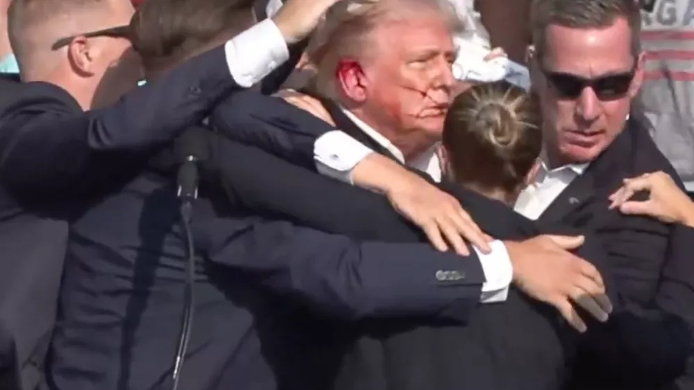 BUTLER, PENNSYLVANIA, UNITED STATES - JULY 13: (----EDITORIAL USE ONLY - MANDATORY CREDIT - 'TRUMP CAMPAIGN OFFICE / HANDOUT' - NO MARKETING NO ADVERTISING CAMPAIGNS - DISTRIBUTED AS A SERVICE TO CLIENTS----) A screen grab captured from a video shows Republican presidential candidate former President Donald Trump appears to be injured after gunshots were reported as he is rushed offstage during a rally on July 13, 2024 in Butler, Pennsylvania. Trump was seen bloodied on his right ear as he was being evacuated from the stage, according to social media footage. (Photo by Trump Campaign Office / Handout/Anadolu via Getty Images)