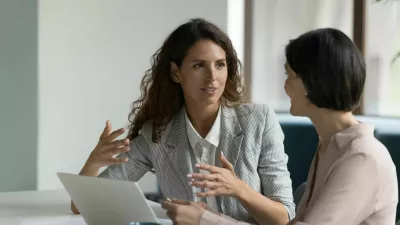 Two business women sit at desk discuss project details, diverse female colleagues met in office, share opinion, working on collaborative task, sales manager makes commercial offer to company client / Foto: Fizkes