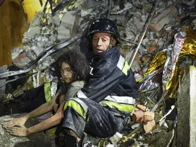 In this photo provided by the National Police of Ukraine on Sept. 3, 2024, a rescue worker pulls out from under the rubble an injured girl at a hotel damaged by a Russian strike in Zaporizhzhia, Ukraine. (National Police of Ukraine via AP)