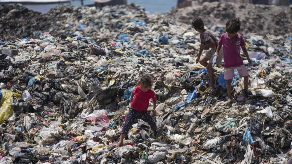 Palestinian kids sort through trash at a landfill in Nuseirat refugee camp, Gaza Strip, Thursday, June 20, 2024. Israel's war in Gaza has decimated the strip's sanitation system while simultaneously displacing the vast majority of the population, leaving many Palestinians living in tent camps nearby water contaminated with sewage and growing piles of garbage. (AP Photo/Abdel Kareem Hana)