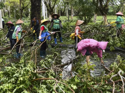 In this photo released by Xinhua News Agency, workers remove fallen tree branches along a street in the aftermath of Typhoon Yagi in Haikou, south China's Hainan Province, Saturday, Sept. 7, 2024. (Yang Guanyu/Xinhua via AP)