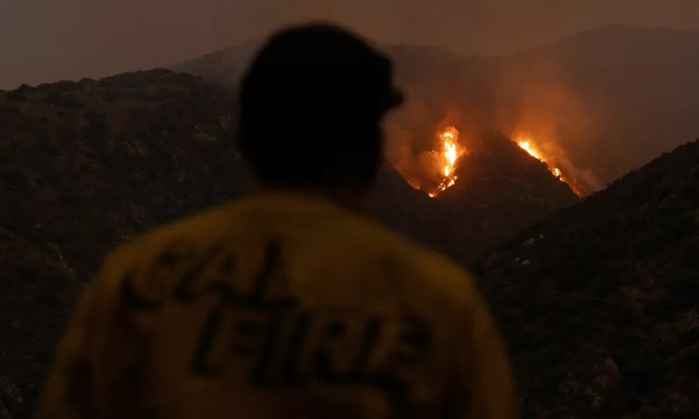 A firefighter monitors the progression of the Line Fire in the San Bernardino National Forest's mountains over Highland, California, U.S. September 8, 2024. REUTERS/Etienne Laurent