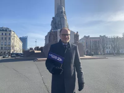 FILED - 28 March 2024, Latvia, Riga: Latvia's Minister of Defence Andris Spruds stands in front of the Freedom Monument with a NATO flag in his hand. Photo: Alexander Welscher/dpa