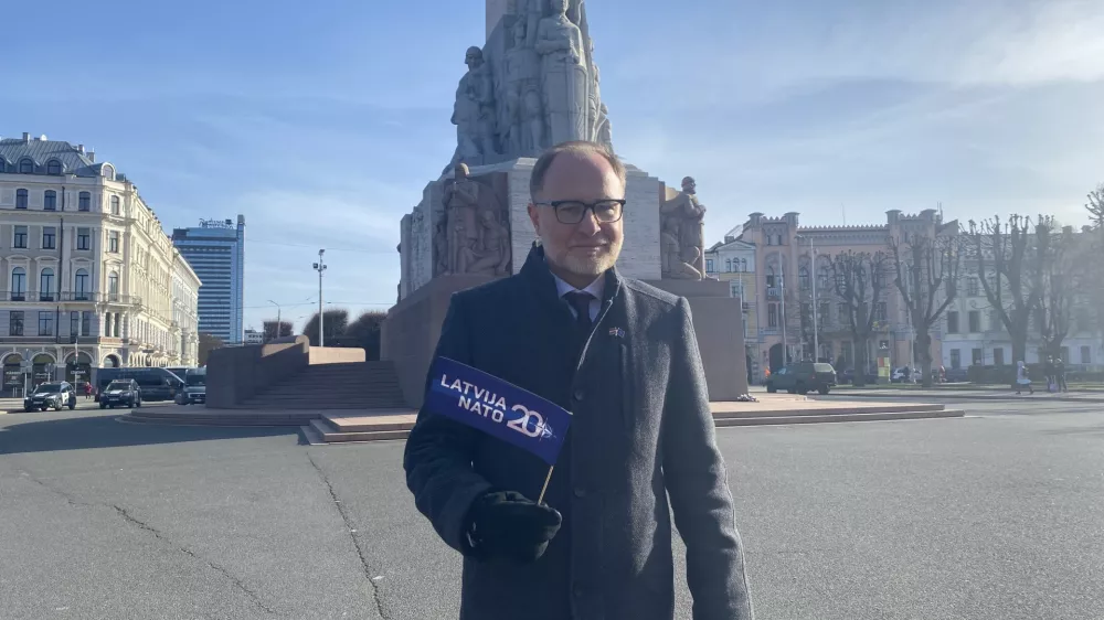 FILED - 28 March 2024, Latvia, Riga: Latvia's Minister of Defence Andris Spruds stands in front of the Freedom Monument with a NATO flag in his hand. Photo: Alexander Welscher/dpa