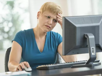 Tensed mature businesswoman using computer at desk in office / Foto: Tetmc