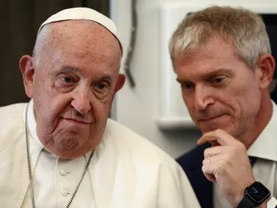 Pope Francis listens to Vatican spokesman Matteo Bruni aboard the papal plane on his flight back after his 12-day journey across Southeast Asia and Oceania, September 13, 2024. REUTERS/Guglielmo Mangiapane/Pool