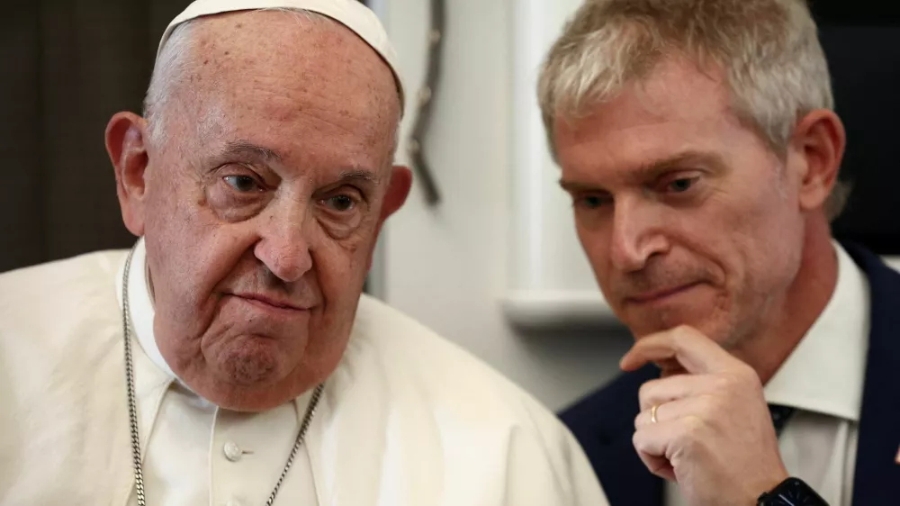 Pope Francis listens to Vatican spokesman Matteo Bruni aboard the papal plane on his flight back after his 12-day journey across Southeast Asia and Oceania, September 13, 2024. REUTERS/Guglielmo Mangiapane/Pool