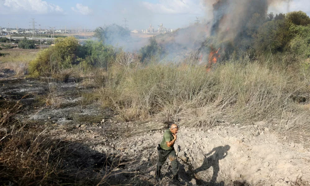 An Israeli policeman walks next to a crater inside an impact spot following a missile attack from Yemen in central Israel, September 15, 2024. REUTERS/Ronen Zvulun