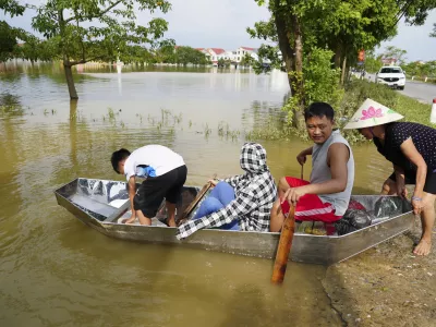 People sit on a boat to get to their flooded homes in the aftermath of Typhoon Yagi in An Lac village, Hanoi, Vietnam Friday, Sept. 13, 2024. (AP Photo/Hau Dinh)