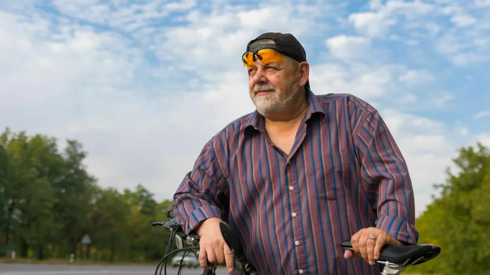 Outdoor portrait of a bearded senior man getting ready to ride on a bicycle / Foto: Yurikr