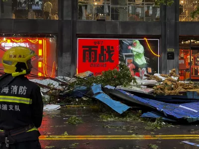 A firefighter stands near debris along a business street in the aftermath of Typhoon Bebinca in Shanghai, China, Monday, Sept. 16, 2024. (Chinatopix Via AP)