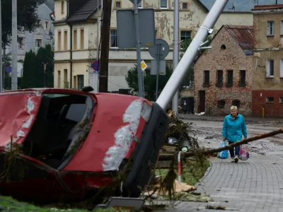 A woman walks near a destroyed car in the aftermath of flooding by the Biala Ladecka River in Ladek Zdroj, Poland September 16, 2024. REUTERS/Kacper Pempel