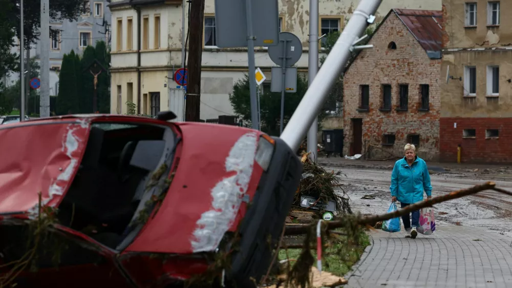 A woman walks near a destroyed car in the aftermath of flooding by the Biala Ladecka River in Ladek Zdroj, Poland September 16, 2024. REUTERS/Kacper Pempel