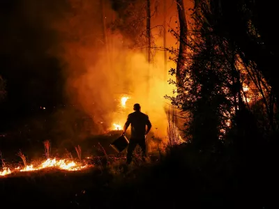 A man holds a bucket during a wildfire in Nelas, Portugal, September 16, 2024. REUTERS/Pedro Nunes